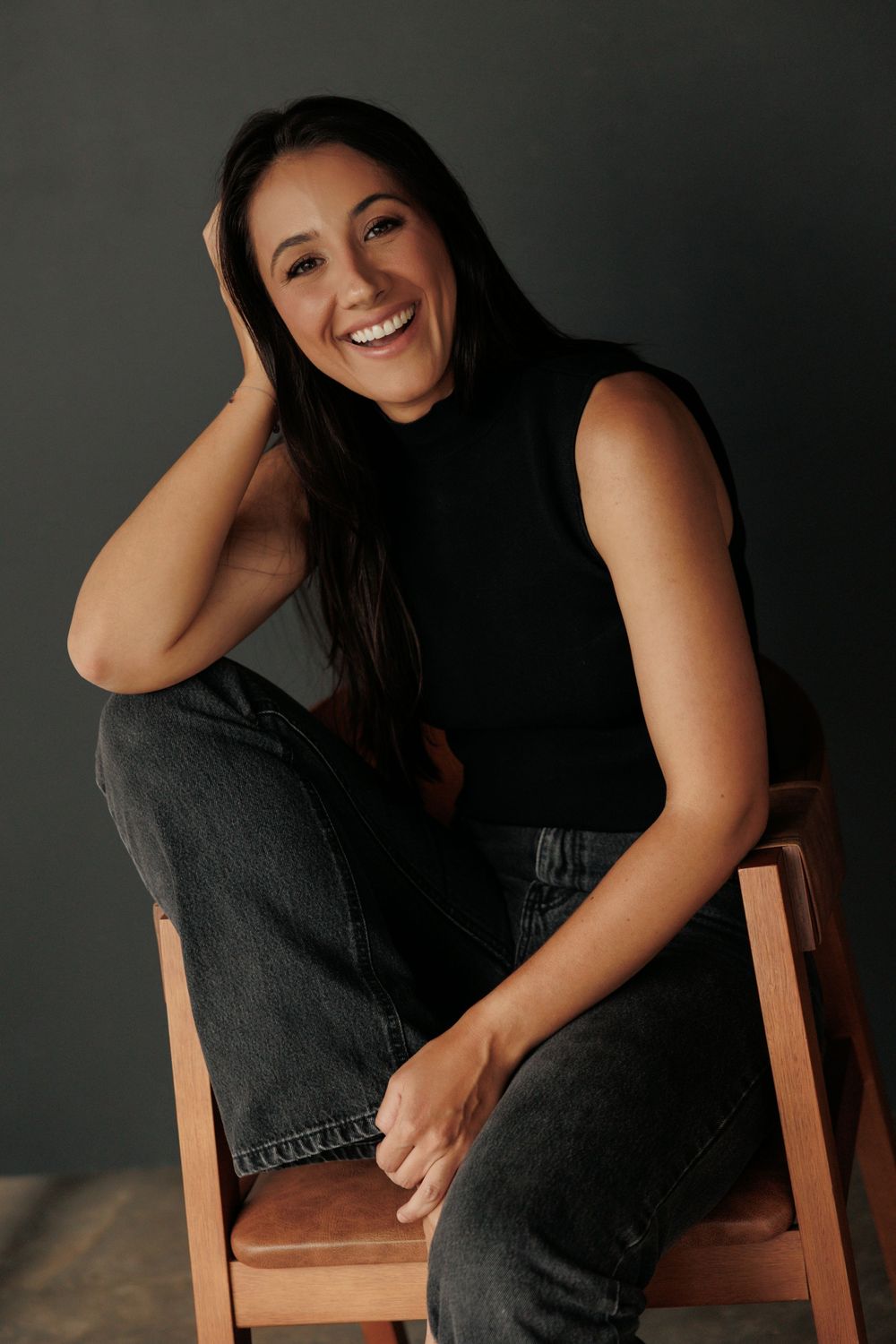 A person in a black dress poses on a wooden chair against a dark background in a series of artistic portraits.