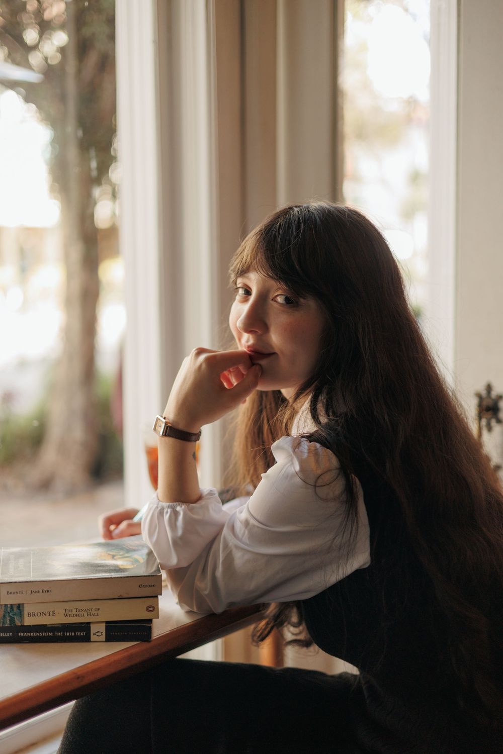 A young woman in white sits by a window, creating a dreamy atmosphere in a sequence of contemplative poses.