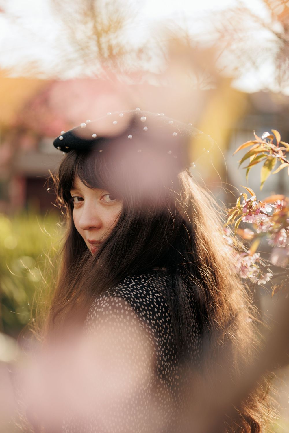 Dreamy portrait with soft bokeh effect showing dark hair and patterned clothing through blurred foreground elements.