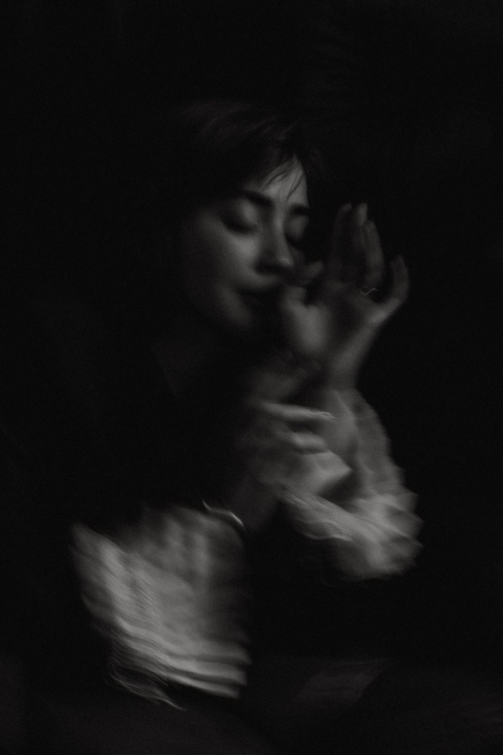 Artistic blurred black and white portrait capturing ethereal movement in darkness.