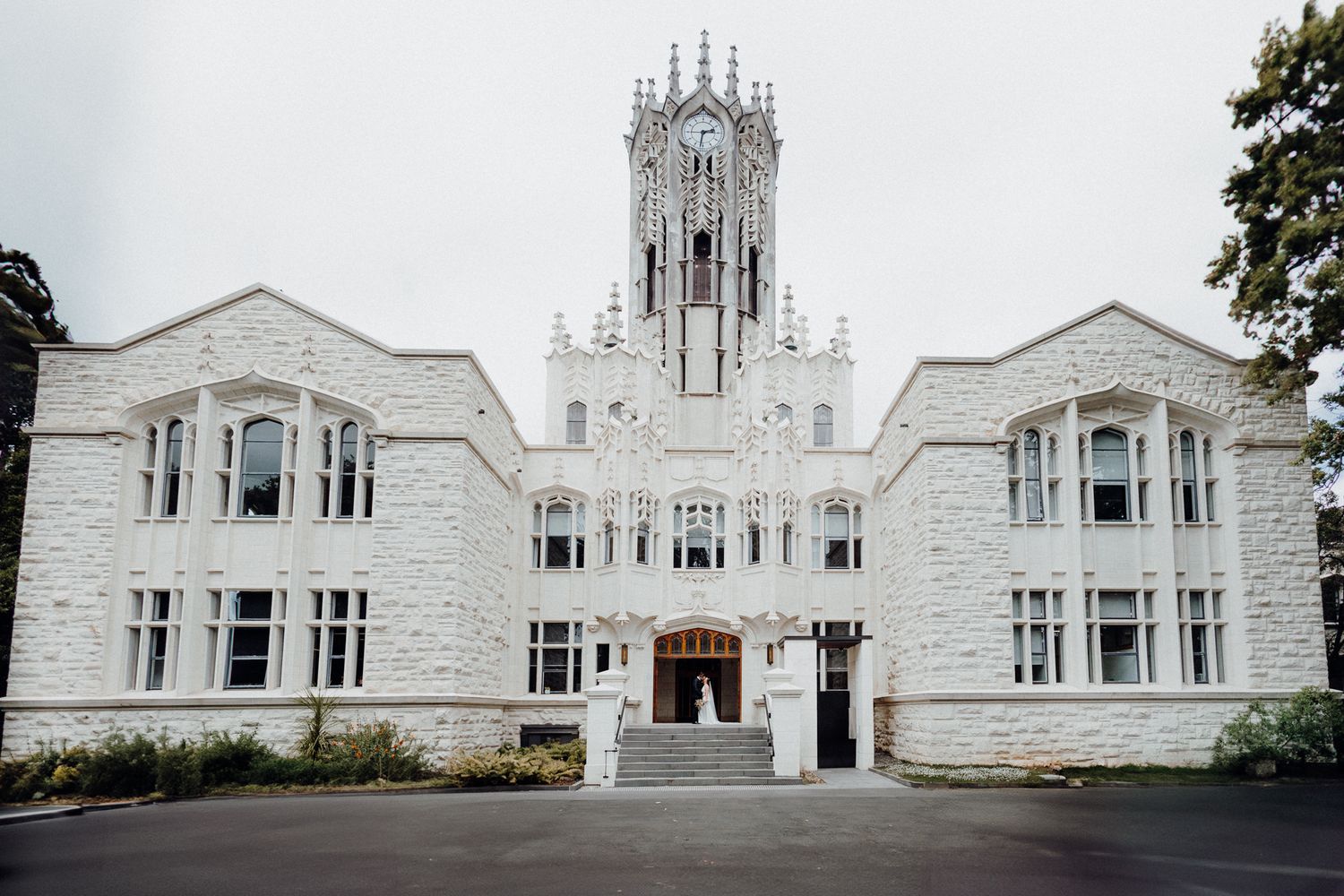 Newly wed in a building with ornate tower and symmetrical architecture, captured by Apertured Media Auckland Wedding Photographer.