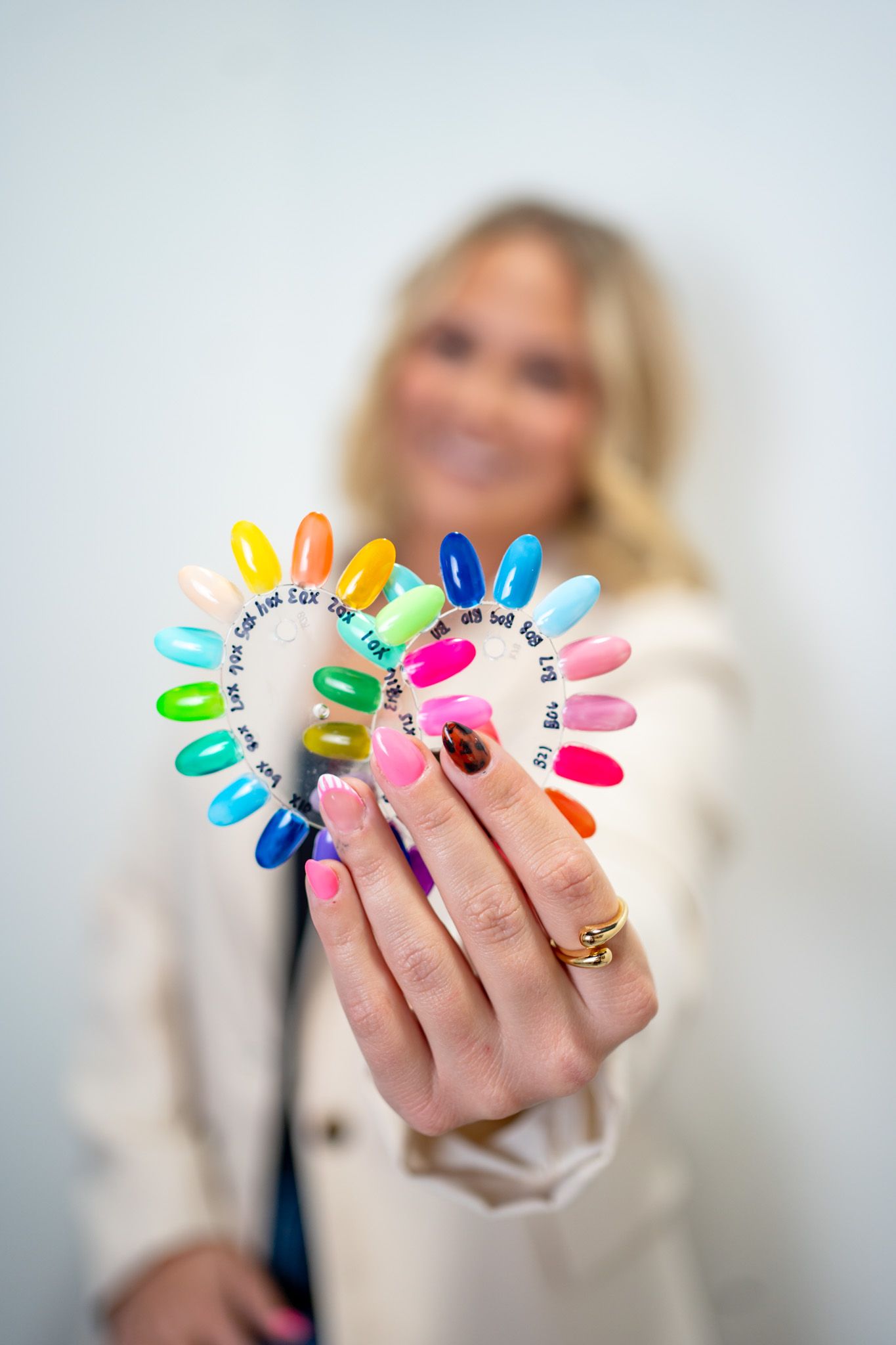 Colorful nail polish swatches arranged in a rainbow semicircle display.