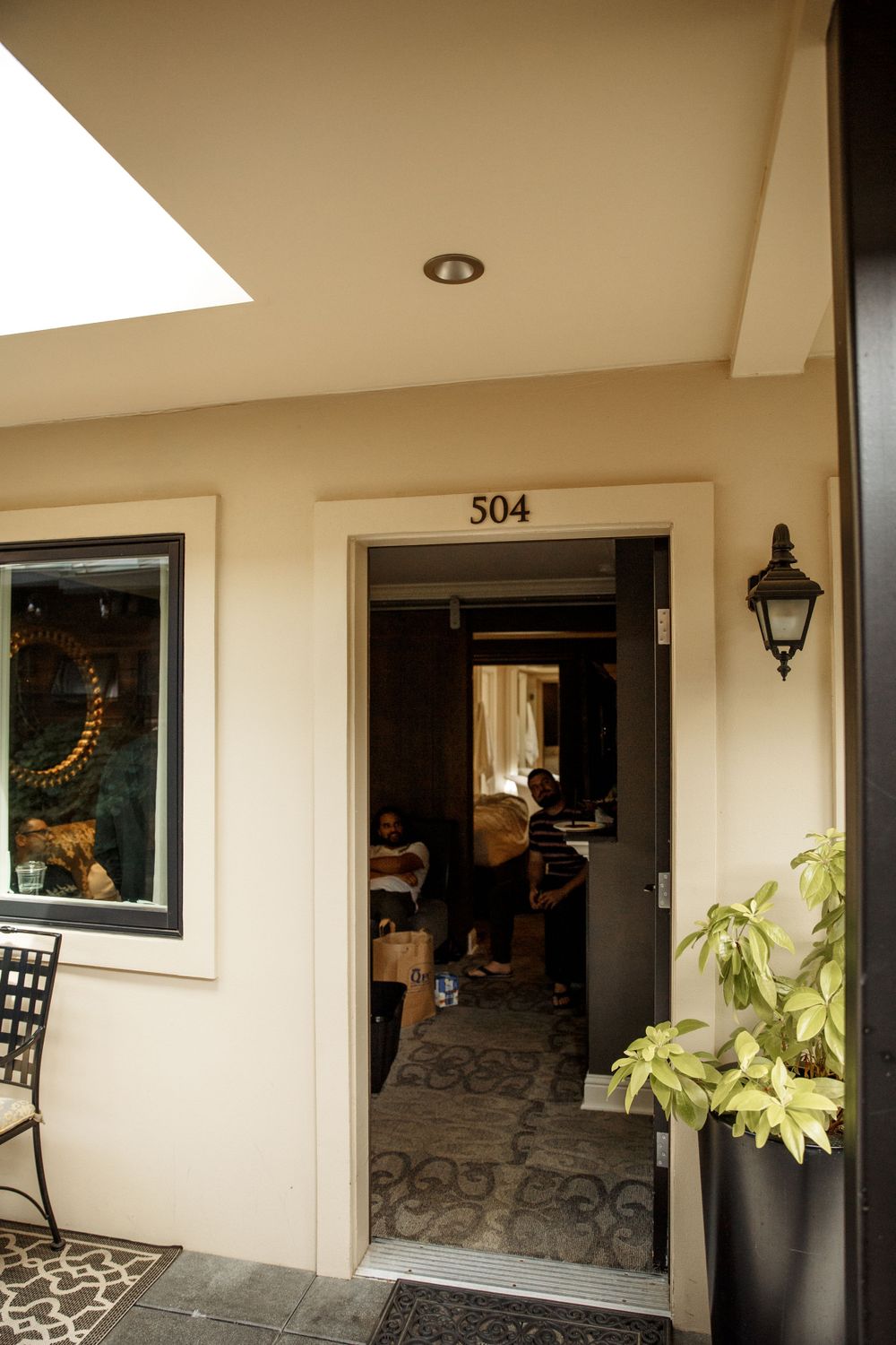 Entrance to room 504 with a black lamp, decorative window, and potted plant beside an open doorway.