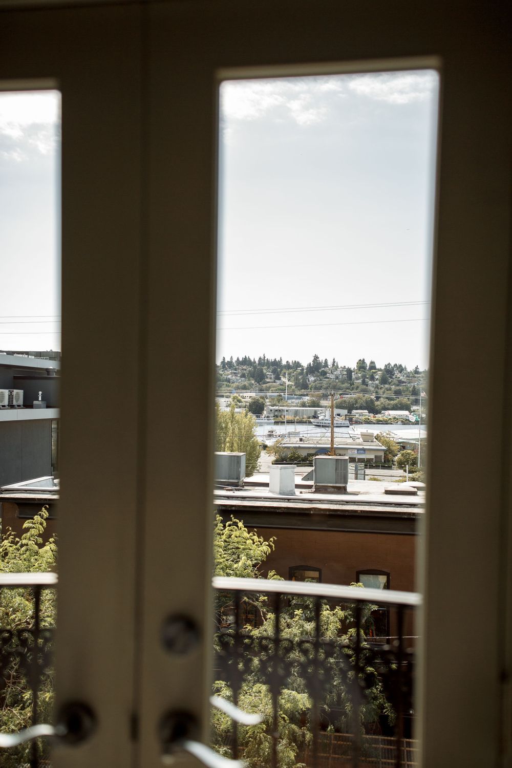 City skyline and rooftops viewed through French doors on a sunny day.