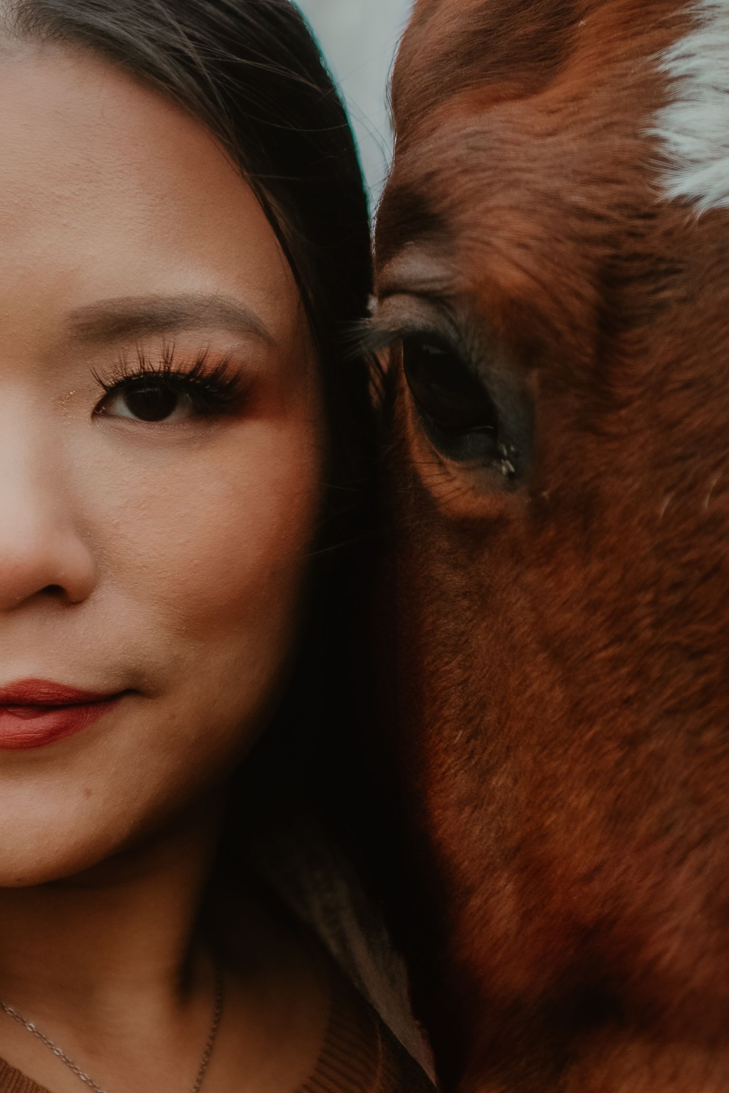 An artistic close-up portrait showing half a face beside a horse's eye.