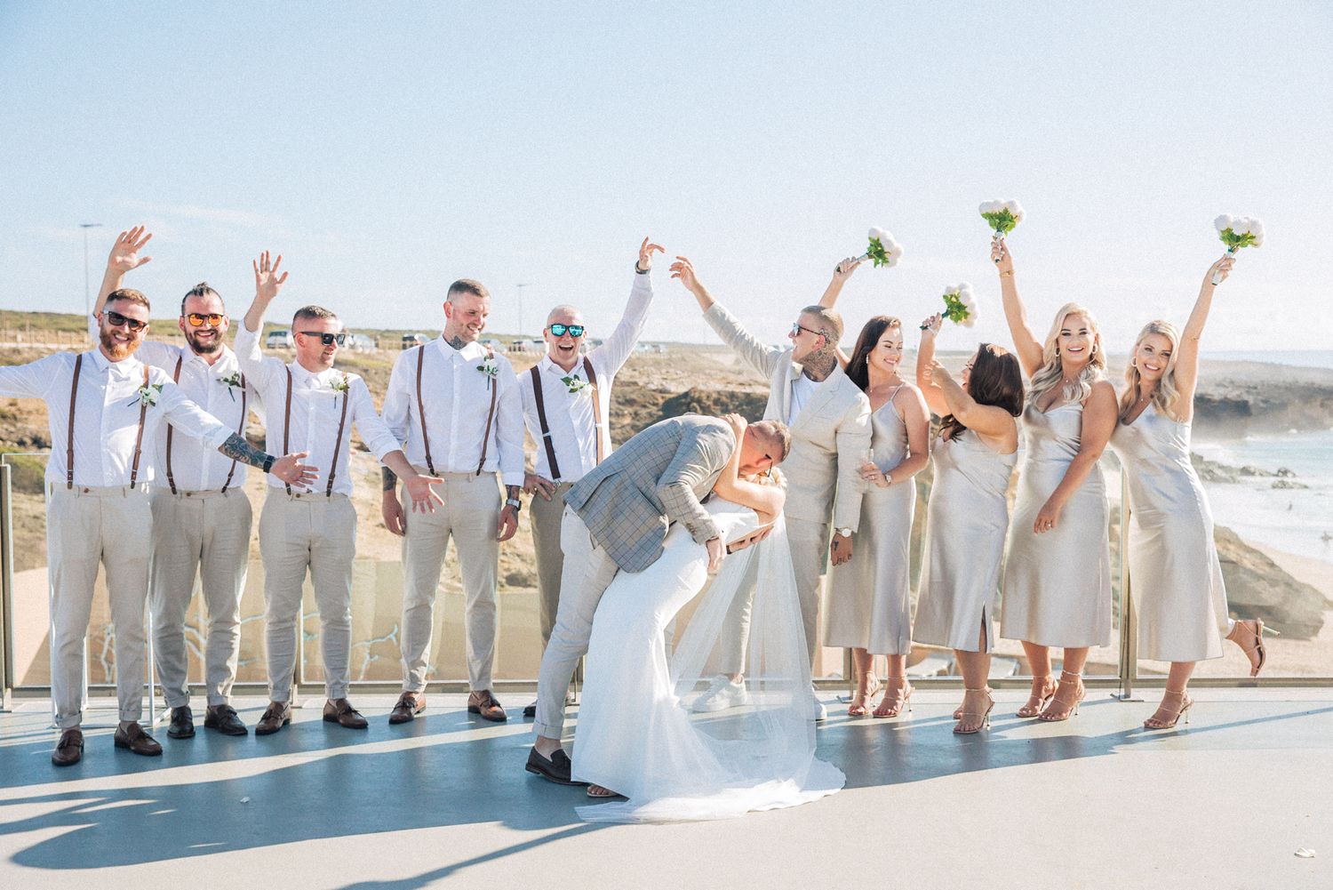 Bridal party in white dresses in celebration on coastal cliff at Arriba by the Sea—captured by a  Portugal destination wedding photographer
