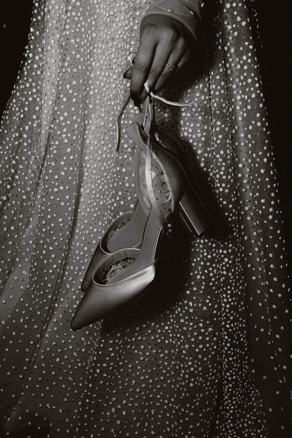 Black and white detail shot of sparkly heels against a twinkle light backdrop.
