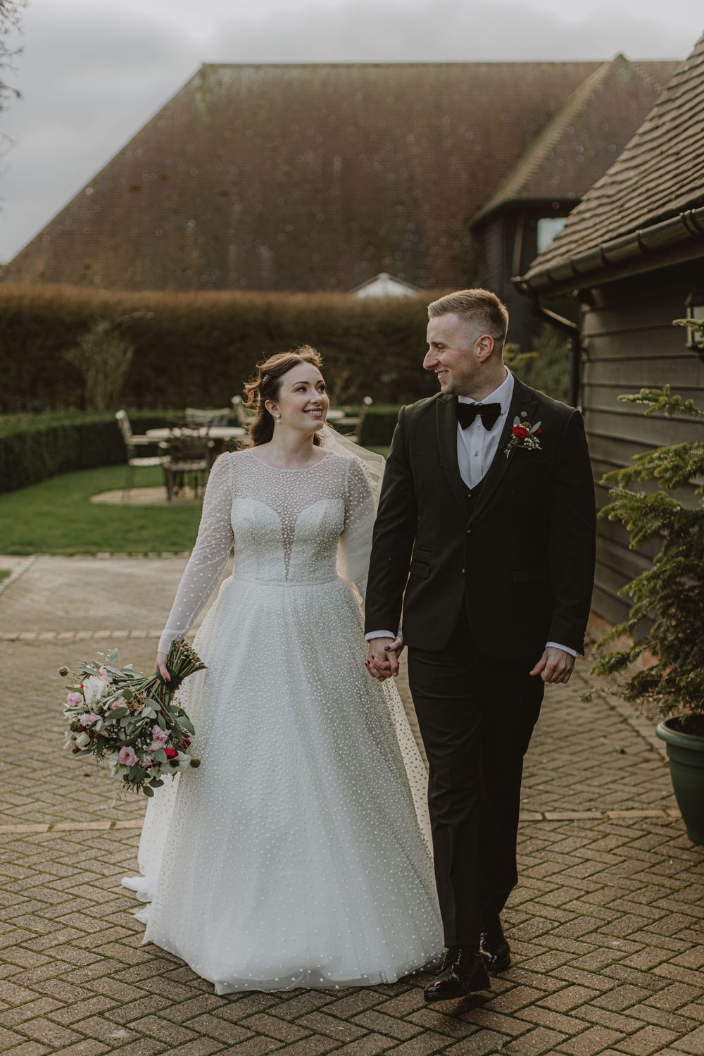 Couple walking on stone pathway outside rustic venue.