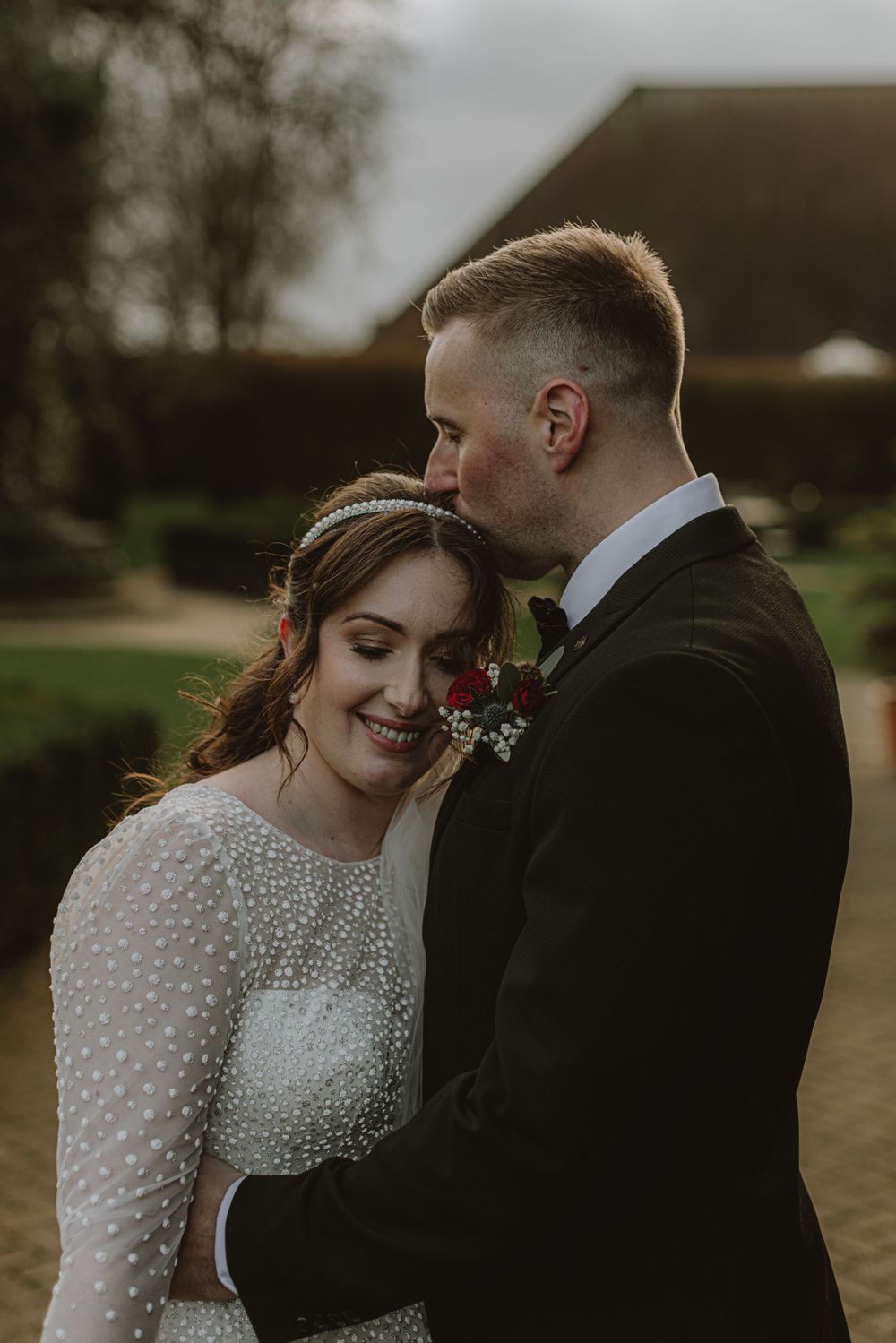 Intimate wedding portrait showing couple in romantic poses with bride wearing beaded long sleeve gown.