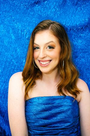Glamorous portraits against vibrant blue backdrop wearing matching blue dress.
