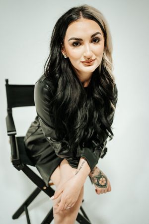 Studio portrait against white background featuring dramatic lighting and black attire.