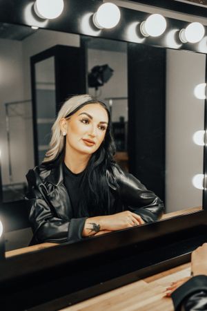 Artistic portrait with dramatic lighting and reflections in dressing room mirror.