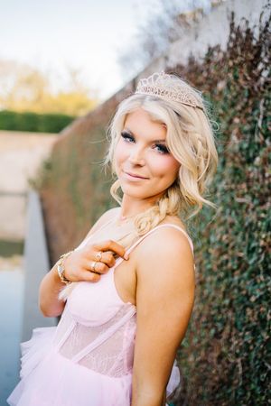 Fashion portrait series of a blonde woman in a pink lace top posing against an ivy wall backdrop.