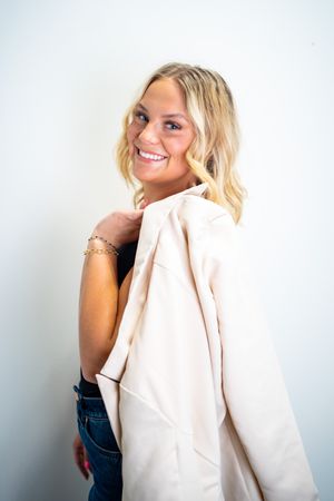 Studio portraits showing playful poses in a white blazer and dark top.