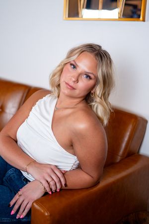 Lifestyle photos of a woman relaxing on a brown leather couch in casual attire.