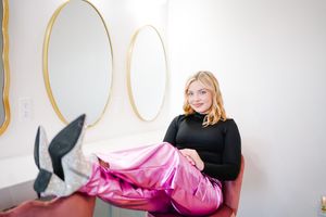 Lifestyle portrait session featuring pink satin skirt and black turtleneck against white backdrop.