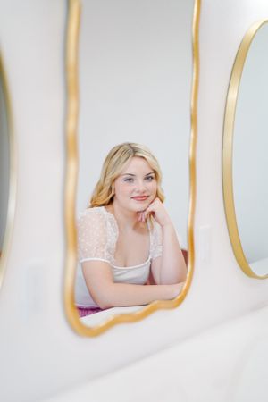 Dreamy boudoir photo with gold-framed mirrors and soft lighting.