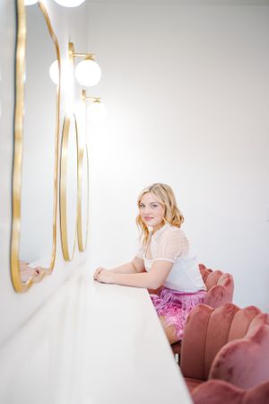 Elegant portrait session on pink velvet couch with decorative gold mirrors.