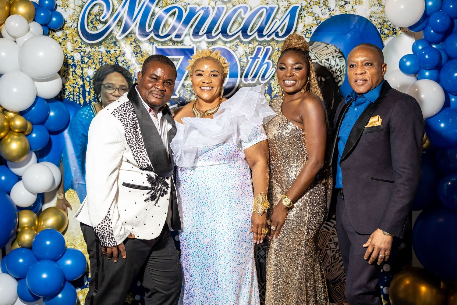 Formal group photo at a 70th celebration with blue and gold balloon decorations.