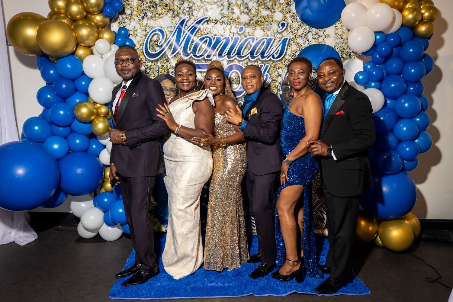Group photo at Monica's 70th celebration with elegant blue and gold decor.