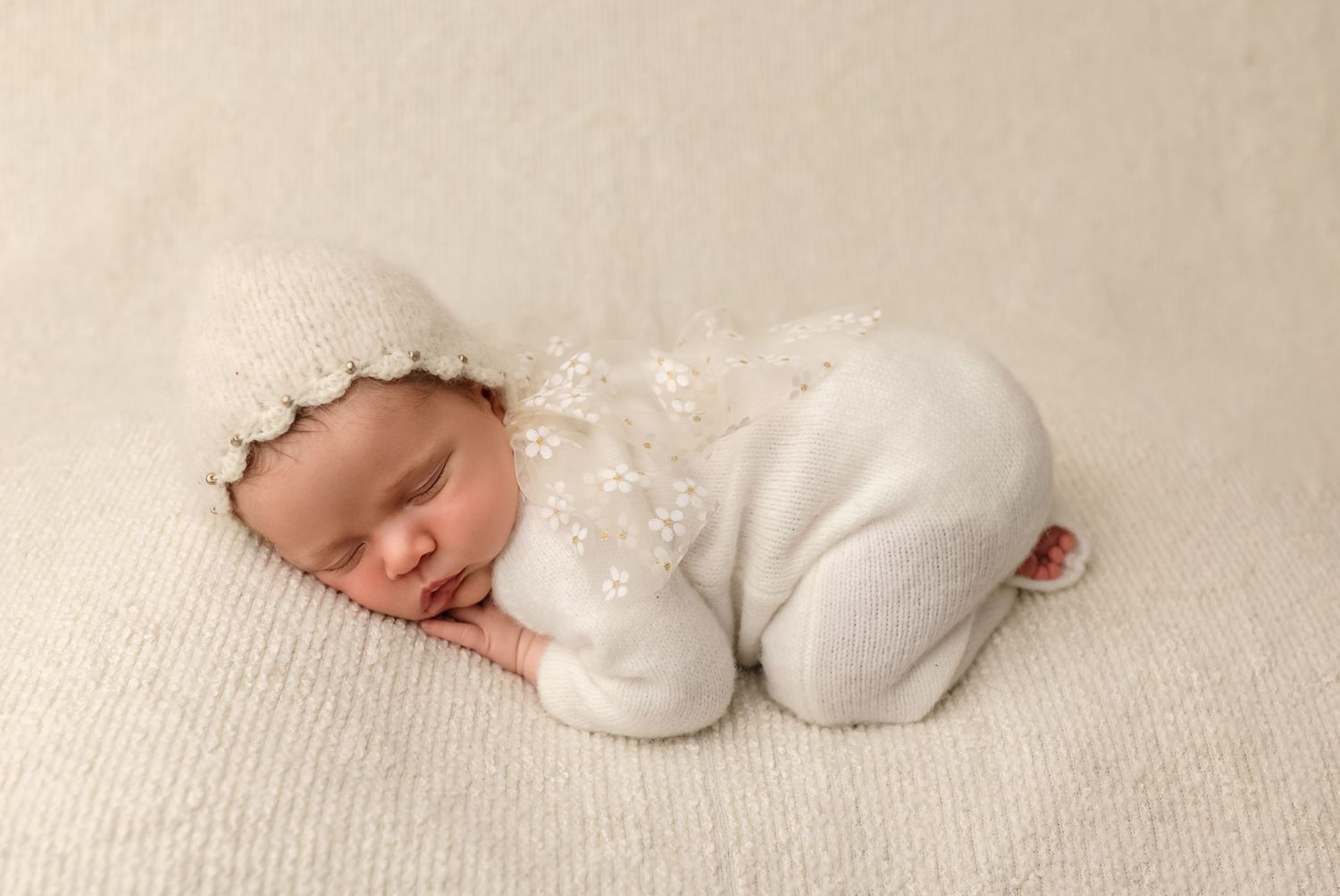 Sweet baby girl in white knits sleeps, bum up, against a white knit backdrop, by Charlottesville newborn and family photographer.