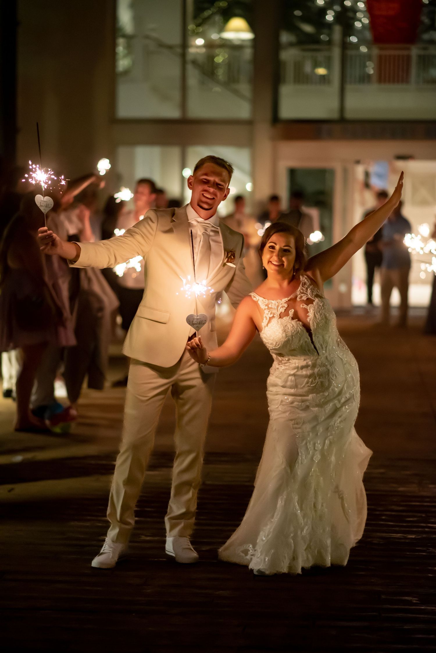 Newlyweds celebrate with sparklers at night during romantic wedding sendoff surrounded by cheering guests.