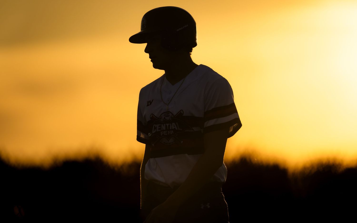 Central Penn Batmen player silhouetted at sunset during a game vs Quakertown, by Deanna Fox, SportsFox Photography, Hershey PA