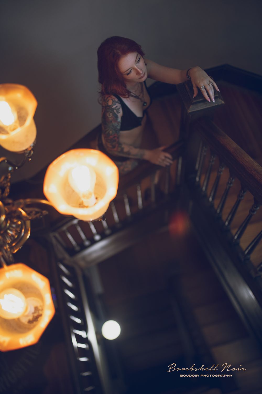 Candlelit boudoir scene with tattoos, black lingerie and orange glowing candles creating moody atmospheric lighting.