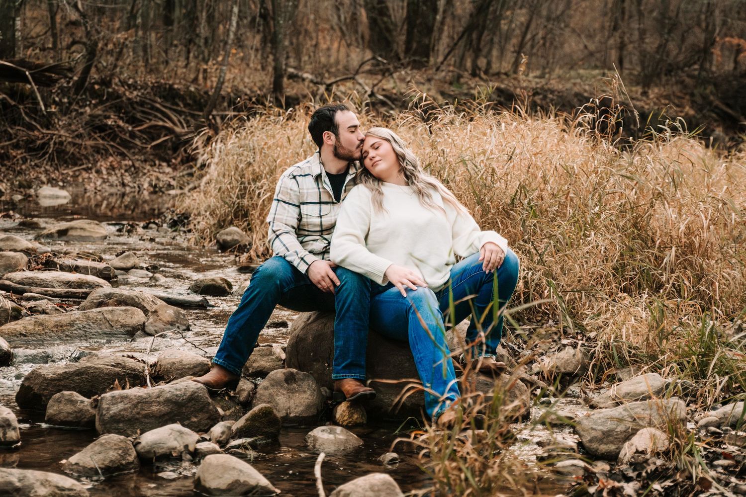 A romantic engagement session captured in a natural setting with rocks and autumn colors.