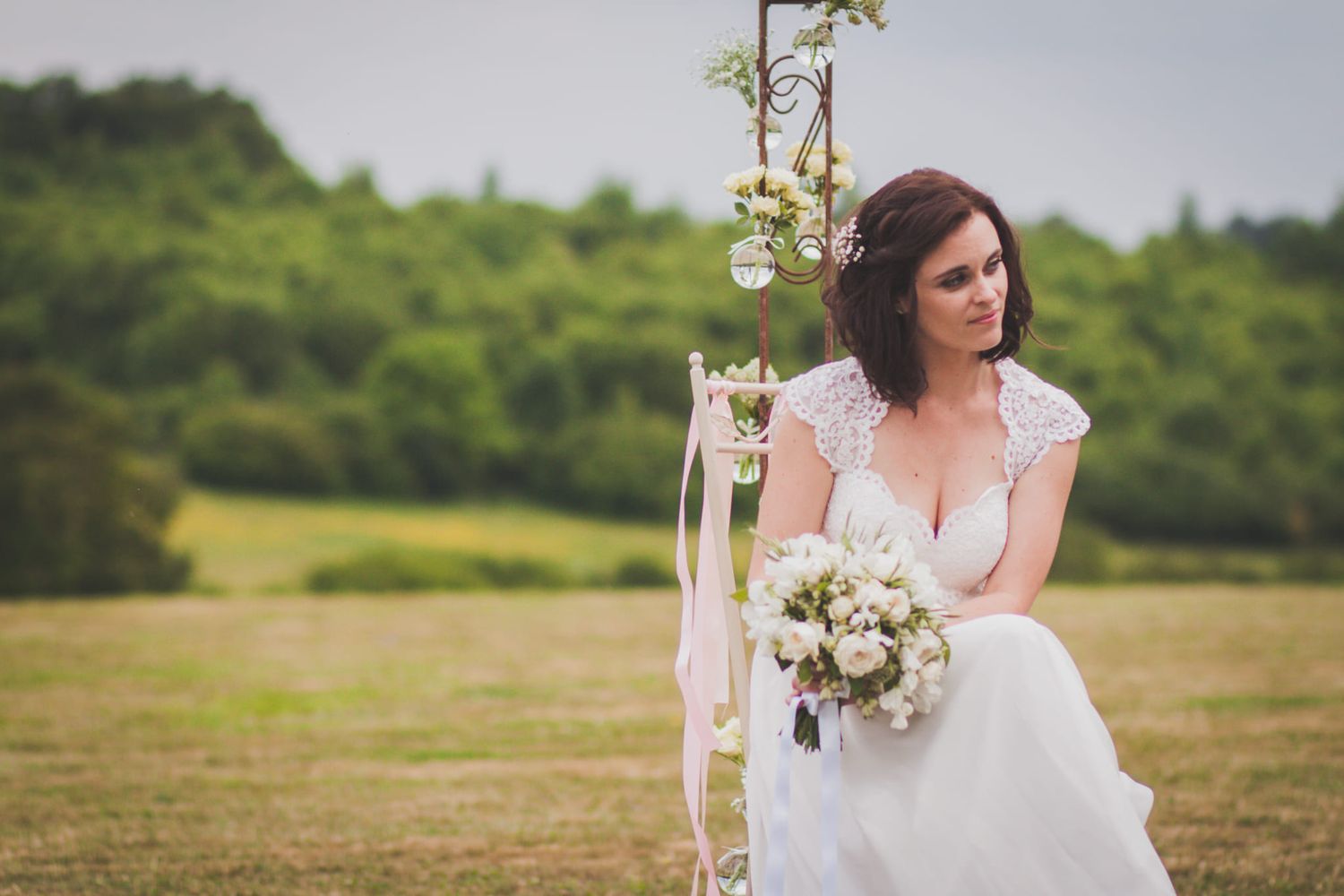 Elegant barn wedding reception with rustic wooden chairs, floral centerpieces, and string lights in a stone venue.