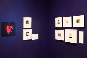 Art gallery with framed photos and Andy Warhol self-portrait print displayed on deep blue walls.