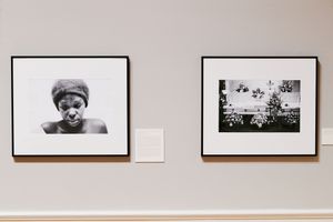 Two black and white framed photographs displayed on a gallery wall, one portrait and one landscape scene.