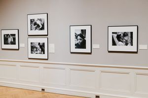 Black and white photography exhibition displayed in elegant gallery with white wainscoting and gray walls.