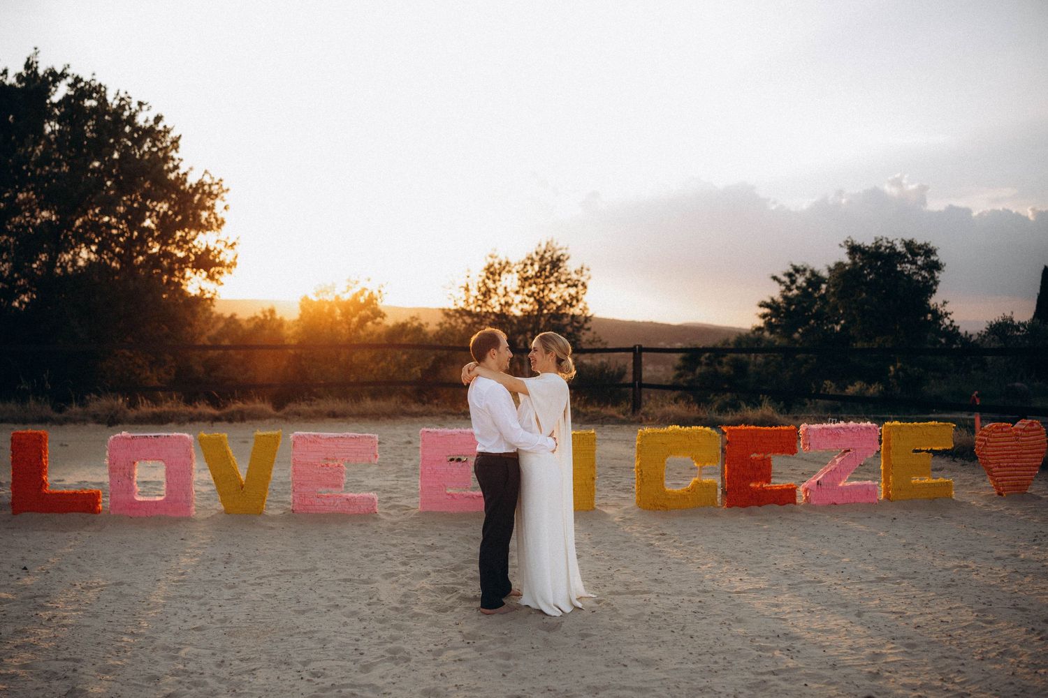 A romantic black and white wedding photograph showing a tender embrace in a natural outdoor setting.