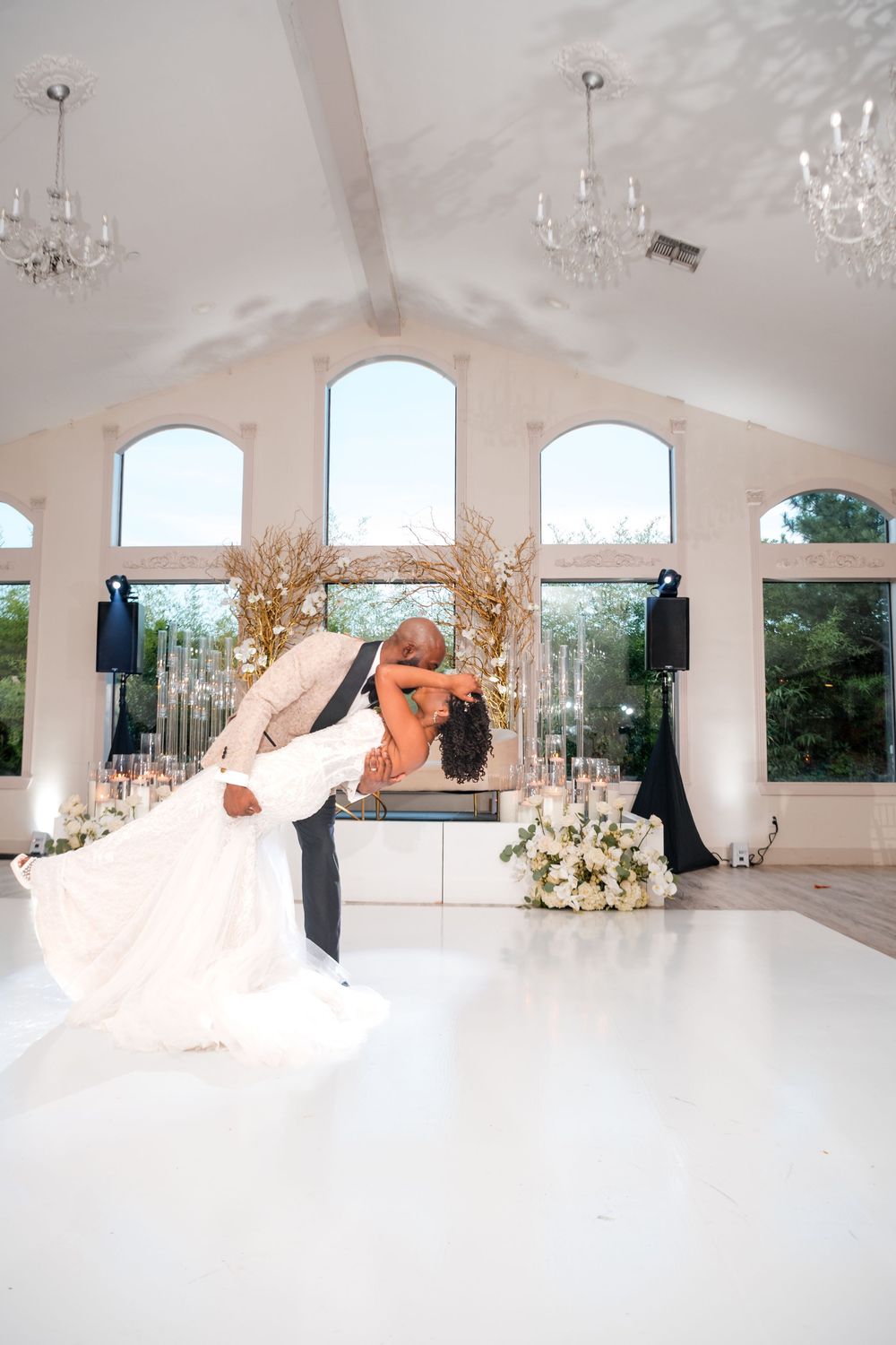 Elegant white wedding venue interior with crystal chandeliers and arched windows creates a romantic atmosphere.