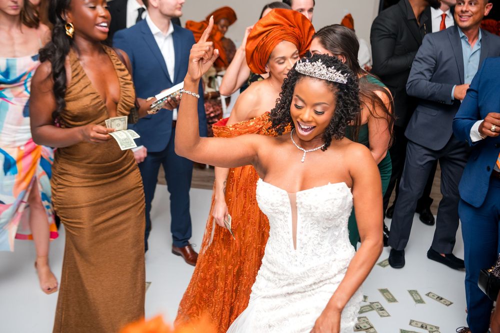 Wedding reception dance floor filled with guests celebrating in formal attire and orange dresses.