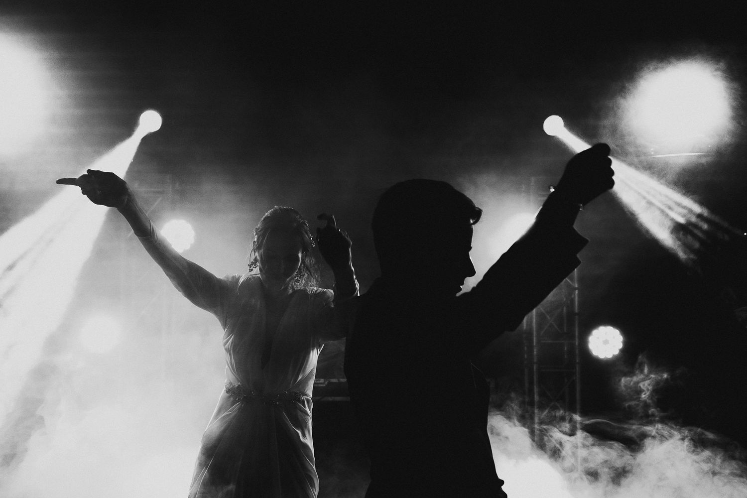 Silhouetted figures celebrating with sparklers against a dark, illuminated background.