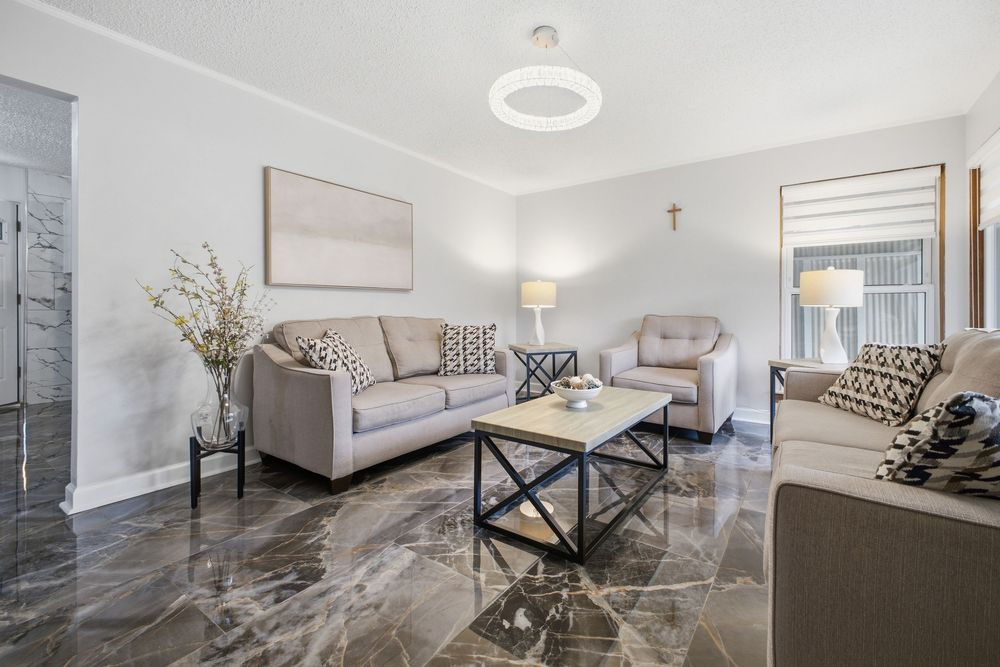 Elegant living room featuring gray sofas, dark marble floors, neutral decor, and a contemporary flush mount ceiling light.