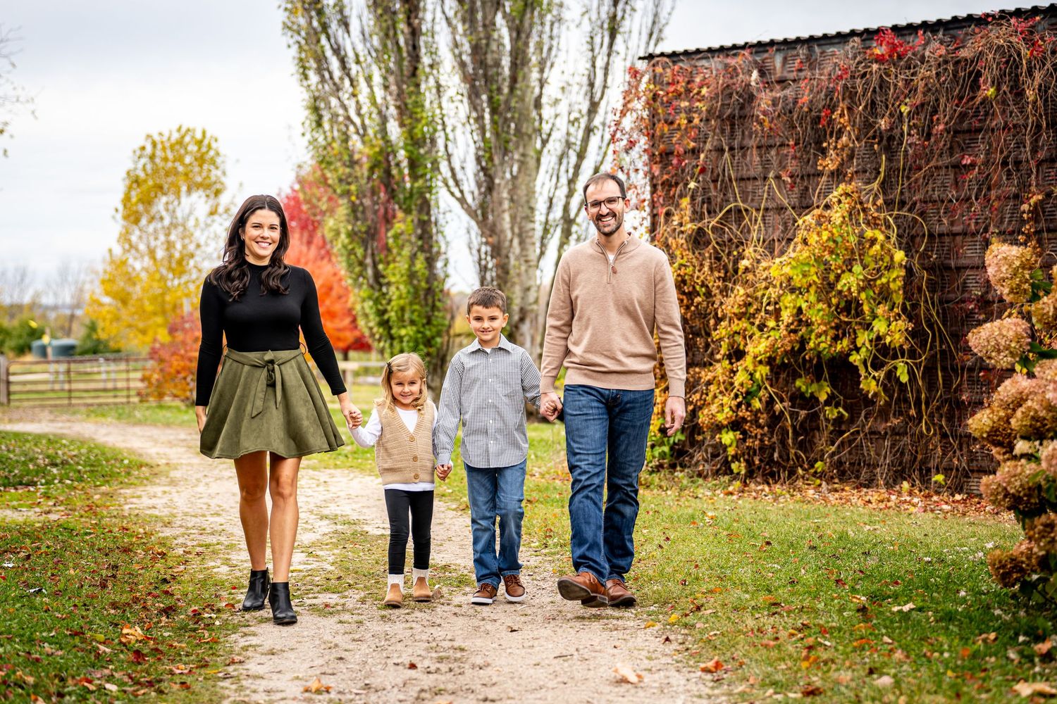 Happy family of four walking together on a path during autumn.