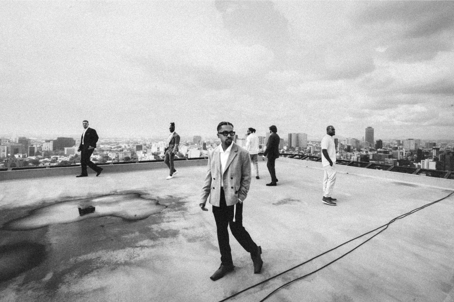 Black and white photo of stylish men on a rooftop with a city skyline backdrop.