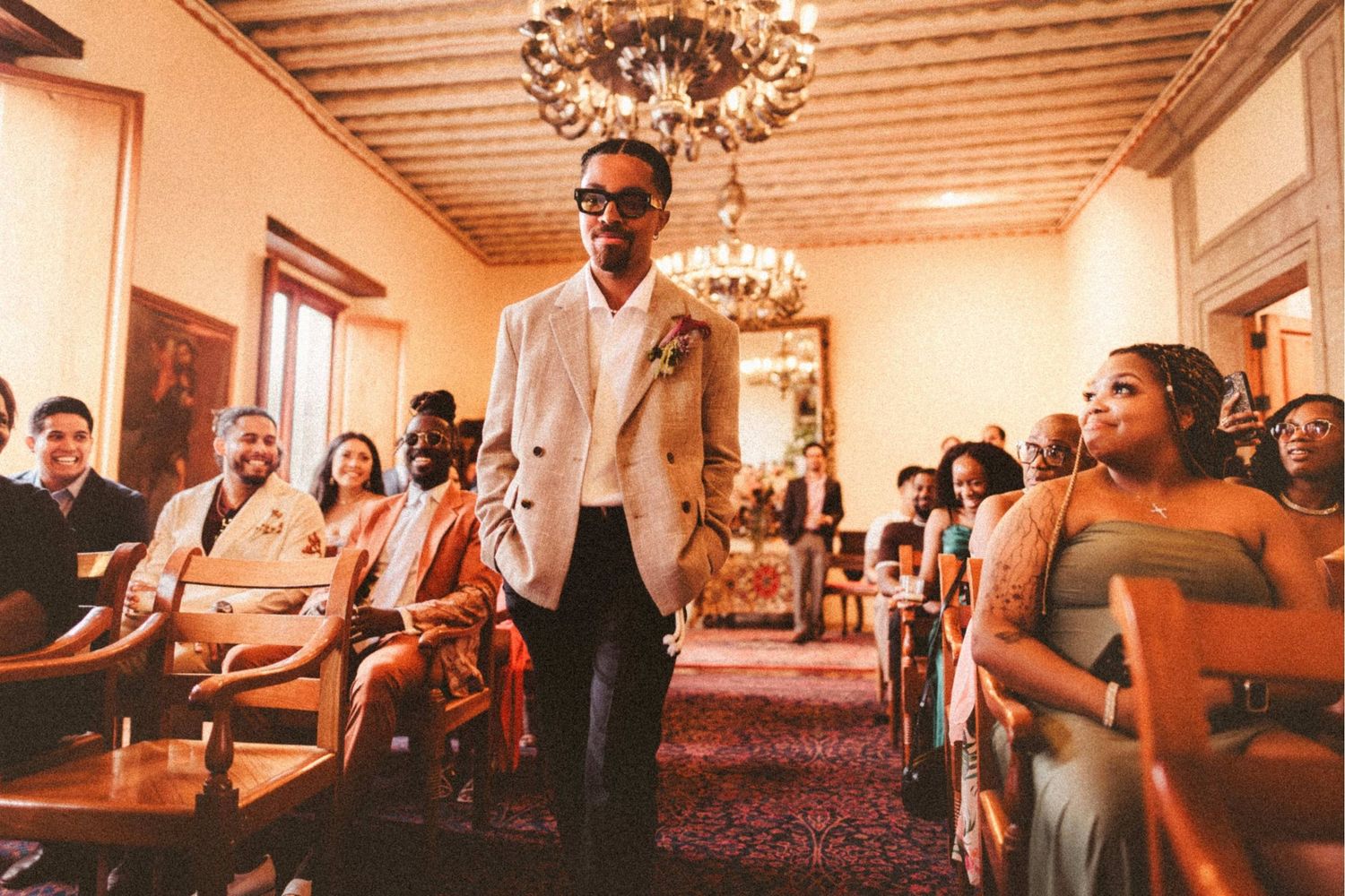 Groom in white blazer walks down the aisle at an elegant wedding ceremony.