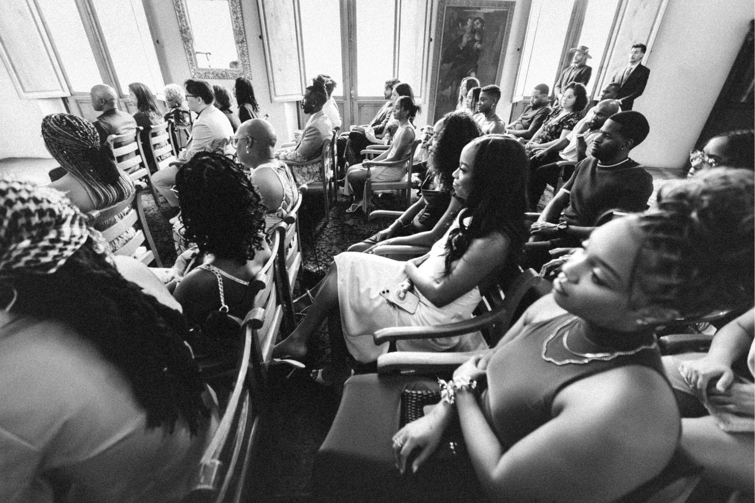 Black and white photo of a diverse audience seated in rows at an indoor event or conference.