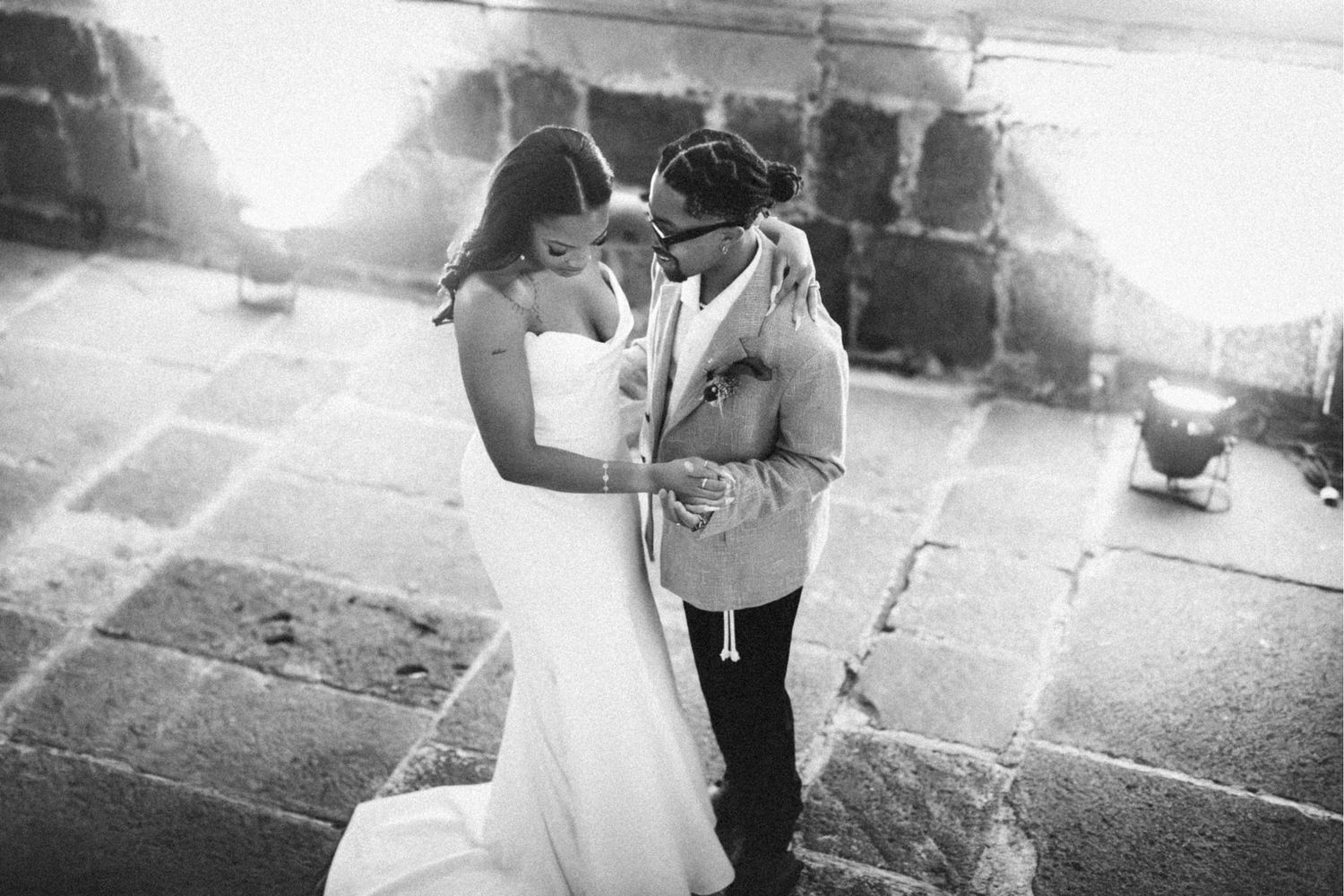Black and white photo of a couple sharing an intimate moment during their wedding dance on stone steps.