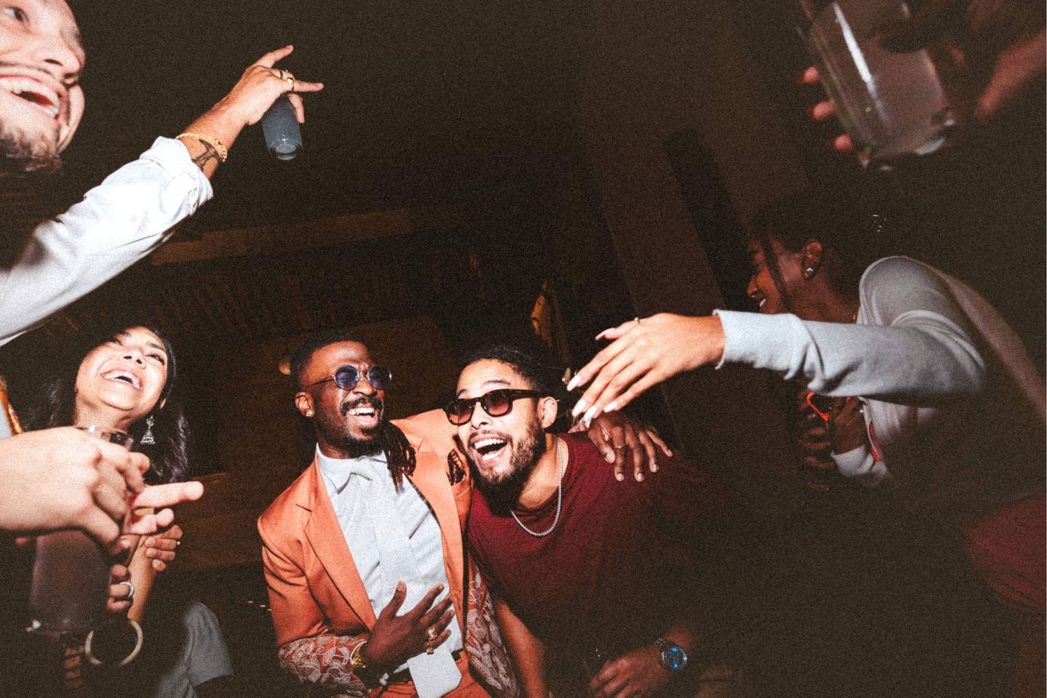 Joyful group of friends dancing and celebrating together at a lively nightclub party event.