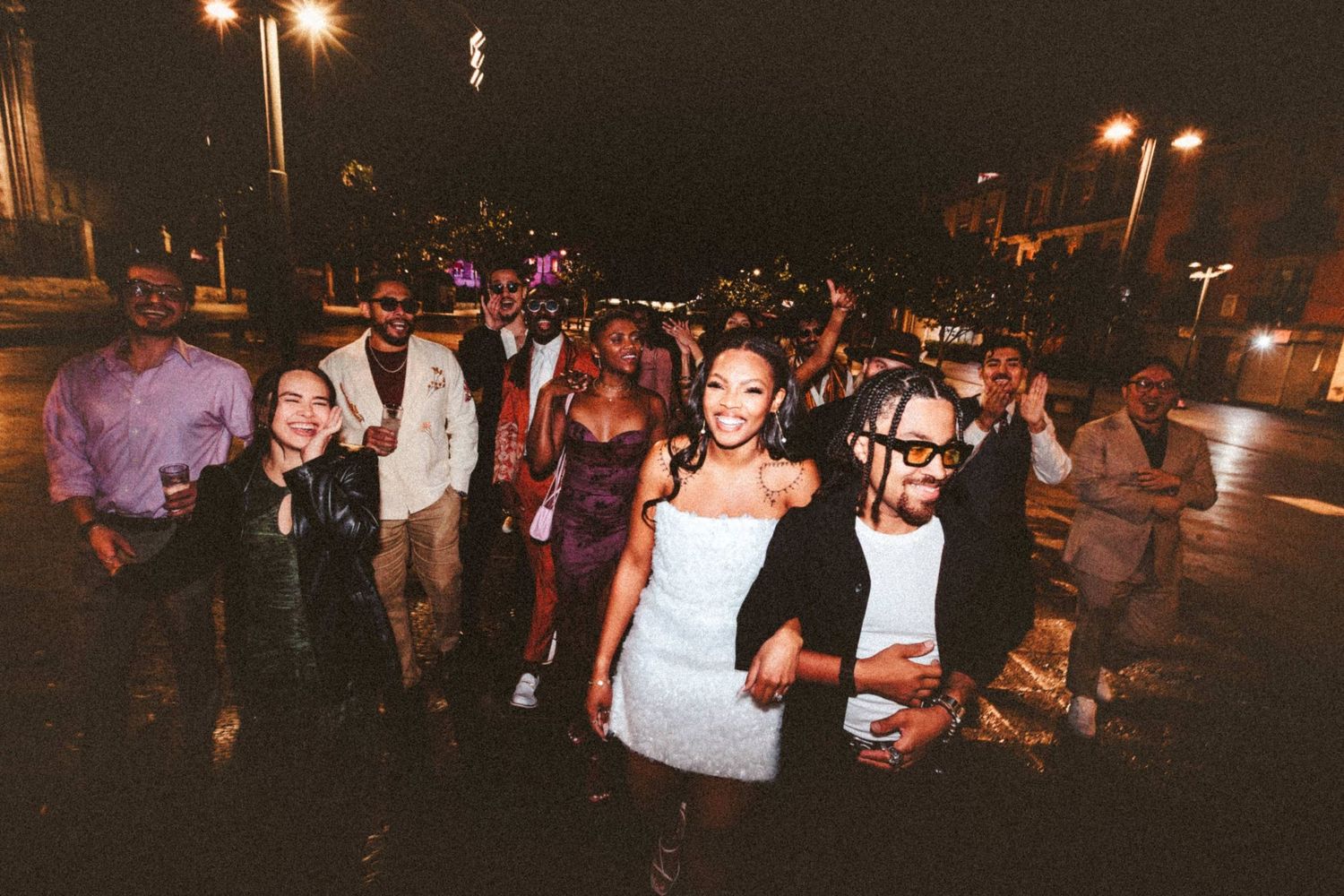 Wedding party and guests walking together outdoors at night, smiling and celebrating after the ceremony.