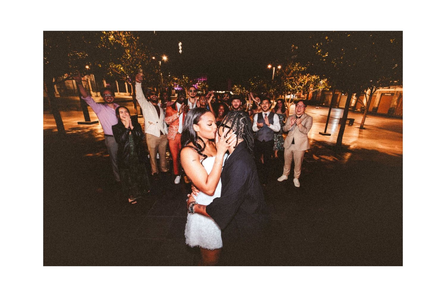 Couple shares first dance outdoors at night while wedding guests celebrate around them.