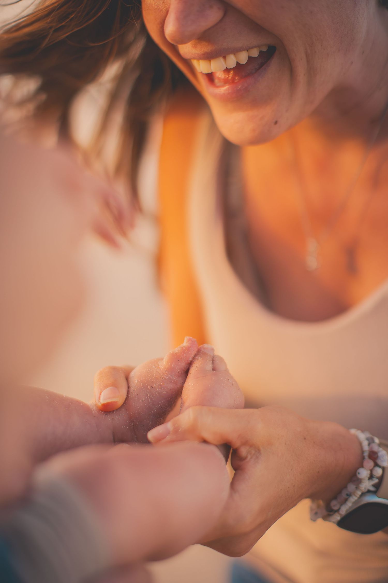 New baby photo with mother holding onto the feet and smiling
