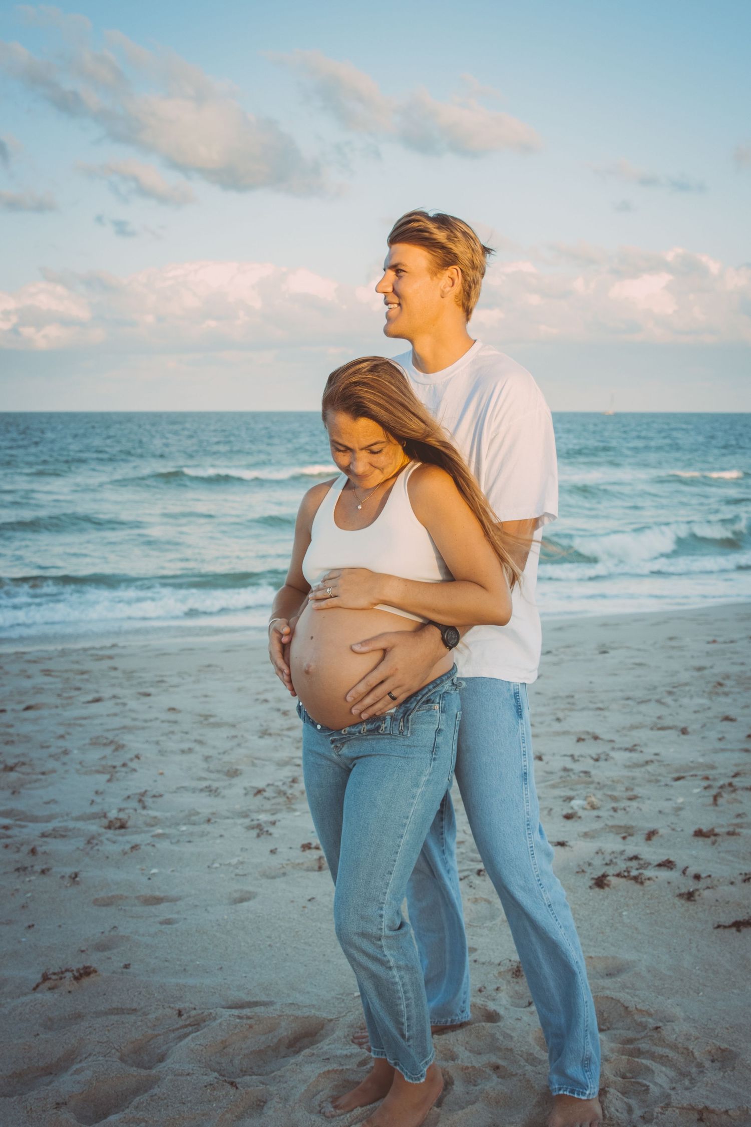 Maternity pictures on a beach in Fort Pierce, Florida, with a husband embracing his wife.