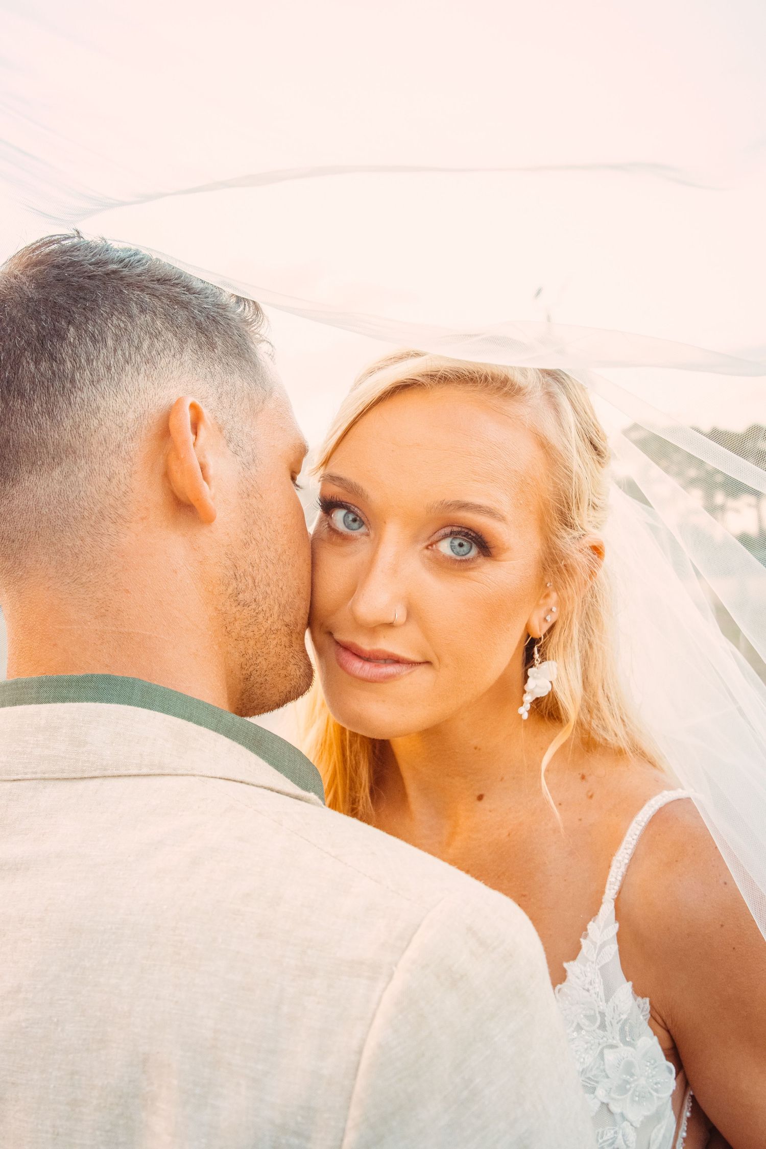 Wedding Photo of a bride in a wedding dress and veil leaning into her husband's cheek and looking up at the camera in rural Florida setting