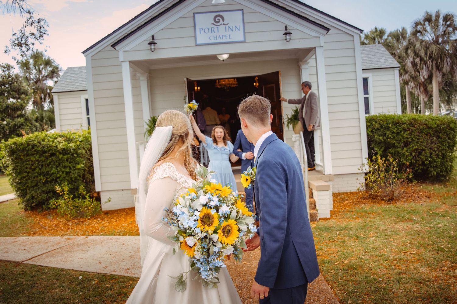 Wedding picture at the Port Inn Chapel in Port St. Joe, Florida, as bridesmaid celebrates the bride and groom outside of the chapel